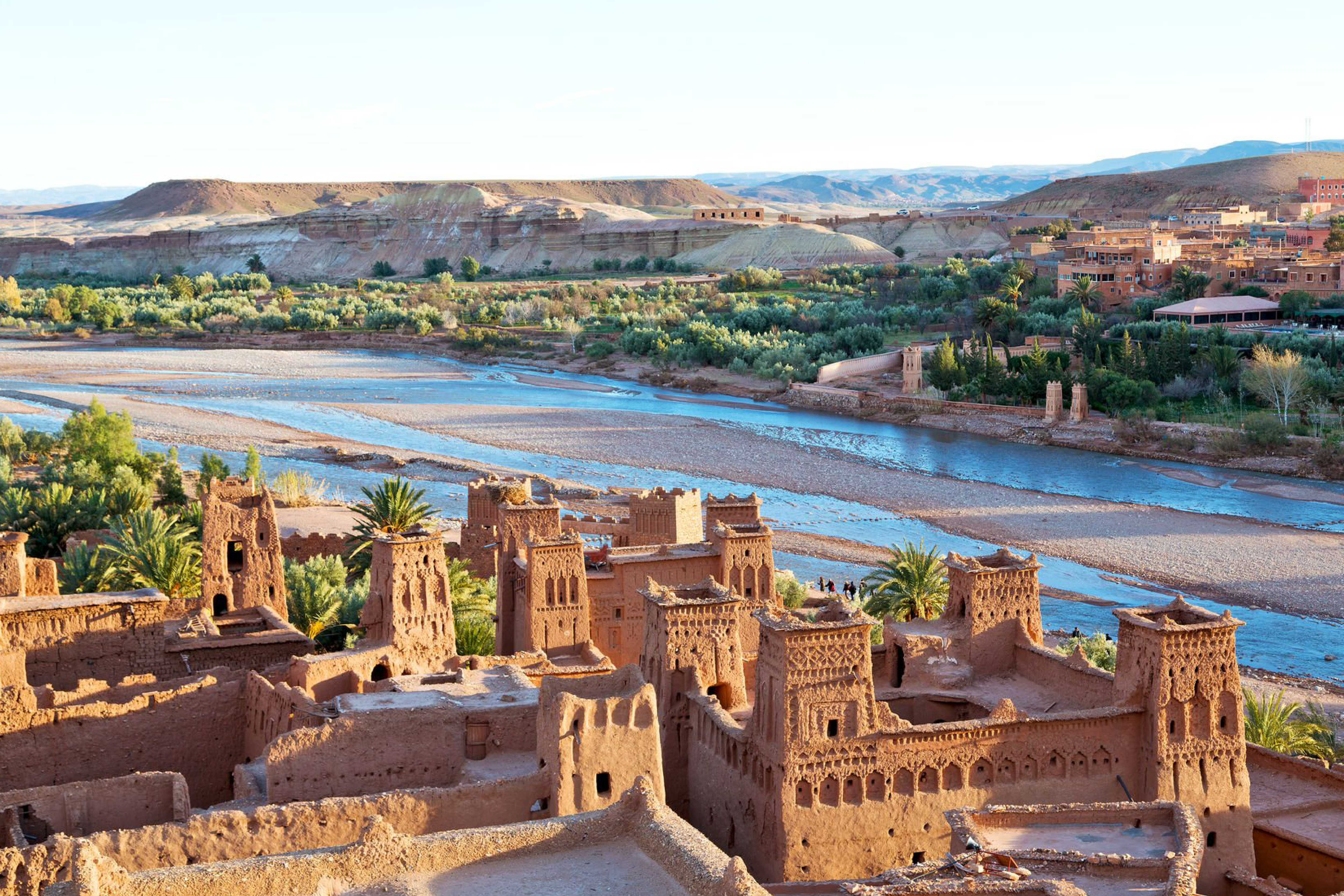 Vue panoramique des kasbahs et montagnes arides de Ouarzazate sous un ciel bleu, idéale pour un voyage organisé depuis Marrakech