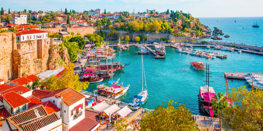 Vue ensoleillée d'une plage méditerranéenne d'Antalya avec palmiers, mer turquoise et ambiance estivale, départ depuis Casablanca